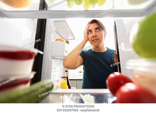 crazy woman at open fridge holding to head