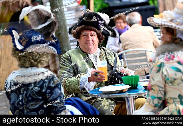 20 August 2021, Brandenburg, Potsdam: Members of the Dresden Baroque Traditional Society sit in the park of Sanssouci Palace at the Potsdam Palace Night