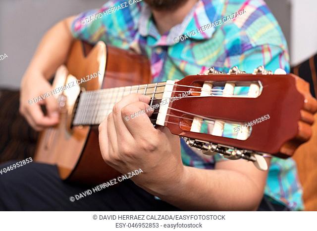 Bearded hipster man hand playing acoustic guitar. Close-up selective focus on hand