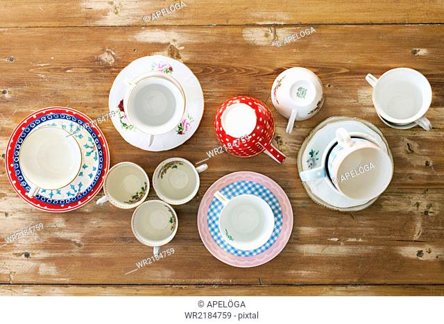 Directly above shot of various tea cups and saucers on wooden table
