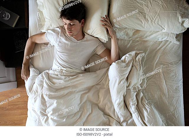Man sleeping alone in double bed