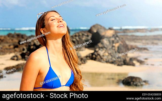 Portrait of young woman sunbathing with closed eyes. Smiling girl tanning sun face skin care