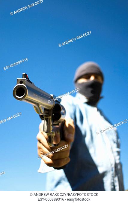 Hooded man with 44 magnum revolver threatening, wide angle view