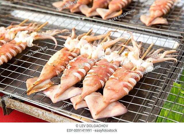 cooking, asian kitchen, sale and food concept - grilled squids at street market