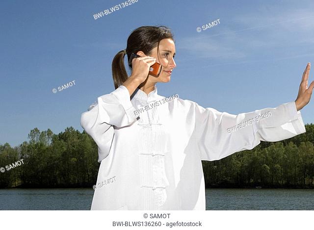 Young woman practising Tai Chi and phoning