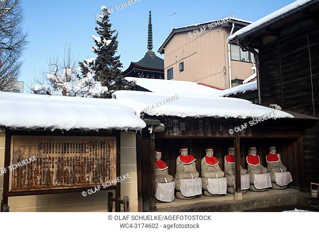 Takayama, Gifu, Japan, Asia - A row of Jizo statues made of stone, wearing red hats and bibs is seen sitting under a wooden shelter at the Hida Kokubun-ji...