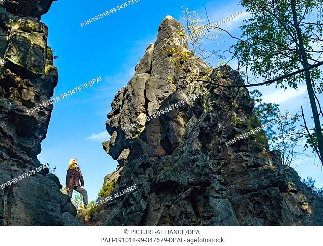 07 October 2019, Saxony, Oybin: A hiker stands between sandstone cliffs near the spa town of Oybin in the Zittau Mountains on the border with the Czech Republic...