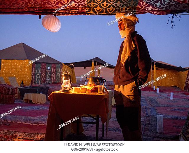 Man in winter clothing, making tea at tent in Erg Chebi, Morrocco