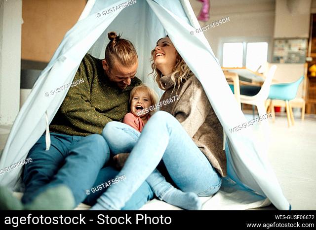 Playful family enjoying inside tent at home
