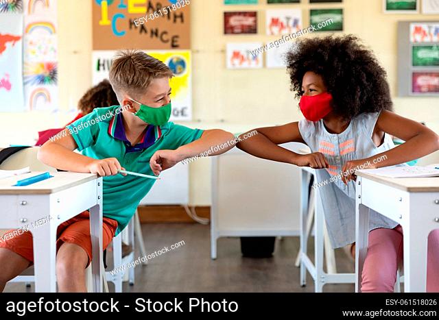Boy and Girl wearing face masks greeting each other by touching elbows at school