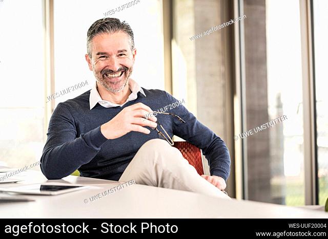 Portrait of a happy mature businessman sitting at desk in office