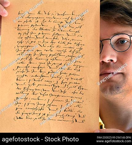 19 August 2020, Saxony-Anhalt, Würchwitz: In the museum of the mite cheese factory Christian Schmelzer holds in his hands a copy of a fragment of a contract of...