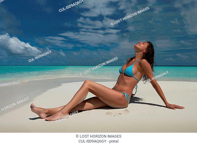 Mid adult woman sitting on beach, Ari Atoll, Maldives