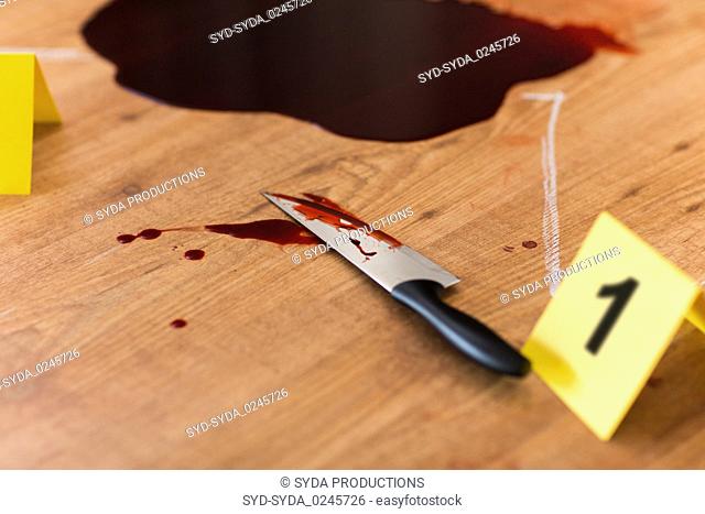 knife in blood and chalk outline at crime scene