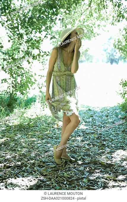 Young woman wearing sundress and sun hat in woods