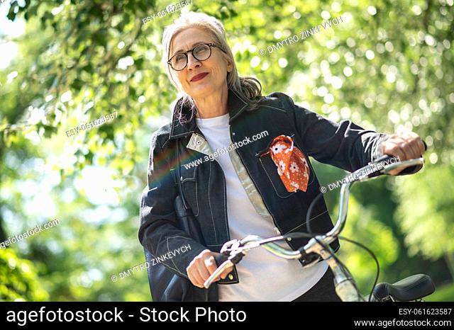 In the park. Mid aged woman with a bike in the park