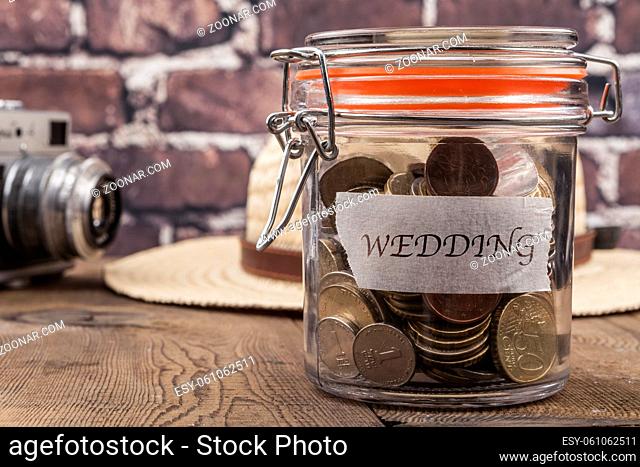 Coins in jar on wood table and brick background
