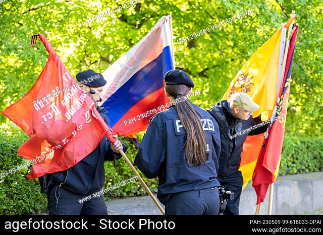 09 May 2023, Berlin: Police officers check a visitor's flags at the entrance to a memorial event at the Soviet Memorial in Treptower Park