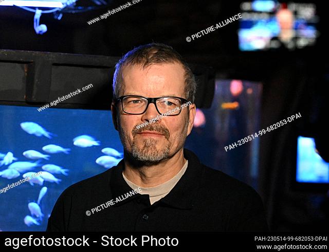 PRODUCTION - 12 May 2023, Berlin: Aquarium curator Martin Hansel stands in front of a tank of the Sealife aquarium in which a swarm of swallowtails (Chromis...