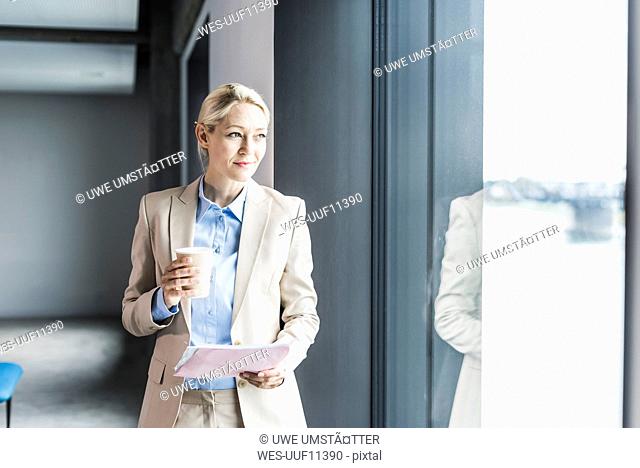 Businesswoman with coffee and documents at the window
