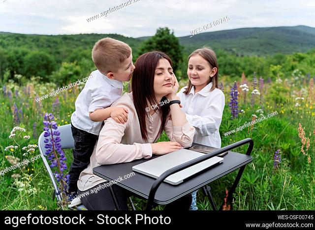 Children irritating freelancer at desk in lupine flowers