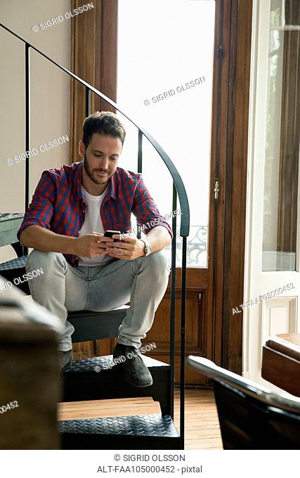 Man sitting on staircase using smartphone