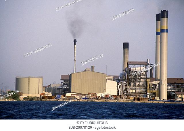 Seawater desalination plant exterior with narrow chimney emitting black smoke