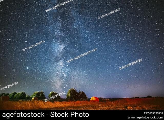 Milky Way Galaxy In Night Starry Sky Above Haystack In Summer Agricultural Field. Night Stars Above Rural Landscape With Hay Bale After Harvest