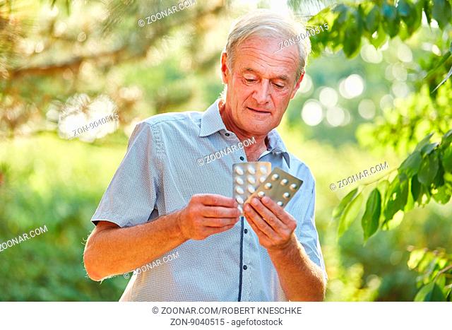 Alter Mann mit Medikamenten in der Hand in der Natur