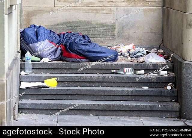 23 November 2023, Hesse, Frankfurt/Main: A homeless man lies amidst garbage on a staircase at Frankfurt Central Station. Caring for people in need becomes a...