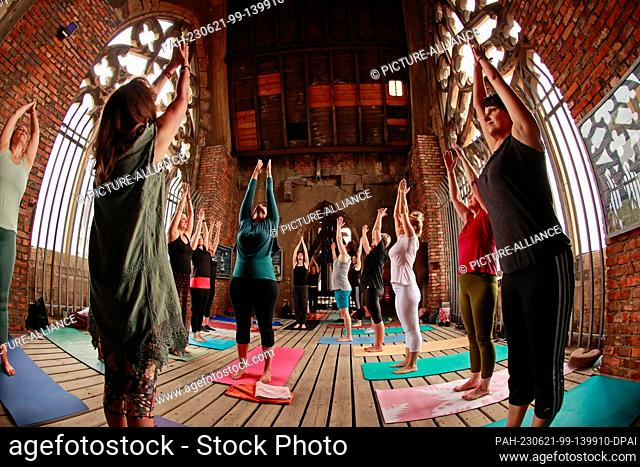 21 June 2023, Saxony-Anhalt, Halberstadt: Participants in a yoga session begin their exercises on the towers of the Martini Church in Halberstadt