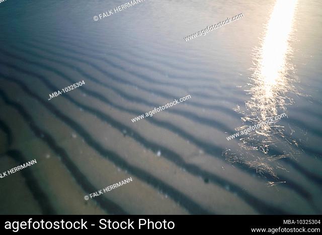 The beach on the Baltic Sea with reflection in the evening light and long exposure, setting sun