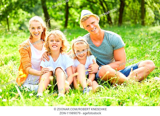 Glückliche Familie und Kinder sitzt zusammen im Sommer im Garten