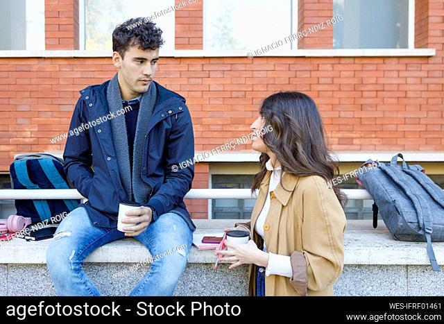 Students talking with disposable cup on college campus