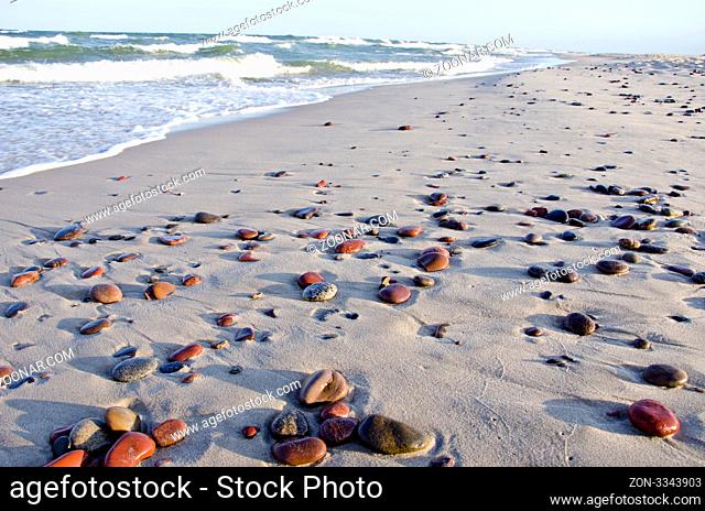 background of seashore little stones beautiful reflections of sun. sea waves beating coast with sand