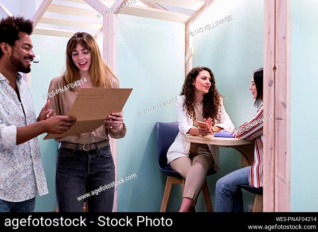 Businessman and businesswoman with document talking in office