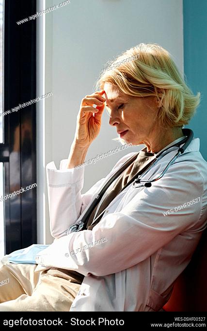 Exhausted doctor with blond hair sitting in clinic