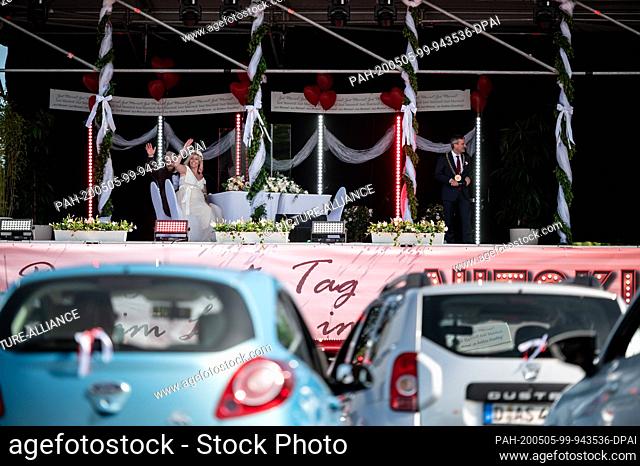 05 May 2020, North Rhine-Westphalia, Duesseldorf: The bridal couple Janine and Philip Scholz (l) sit on stage with Düsseldorf's Lord Mayor Thomas Geisel (SPD)...