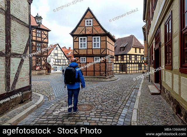 Germany, Saxony-Anhalt, Quedlinburg, a tourist runs along the Finkenkrug, historic lane with half-timbered houses, World Heritage City of Quedlinburg