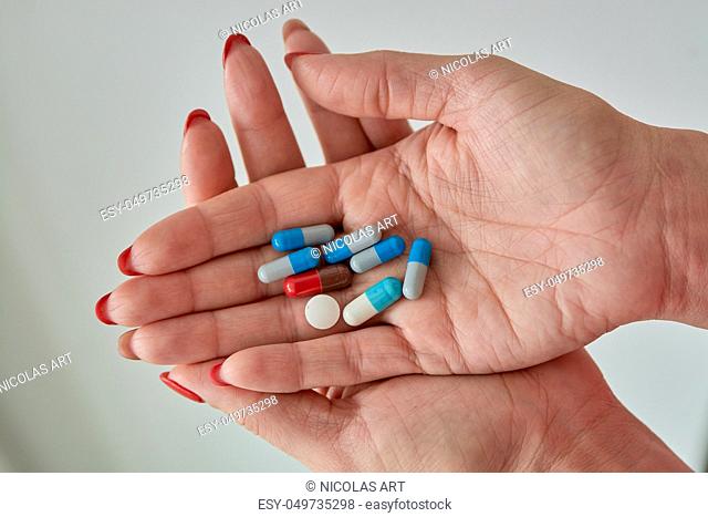 Colored assorted pharmaceutical medicine pills, tablets and capsules on female hand isoleted on white background. Close-up