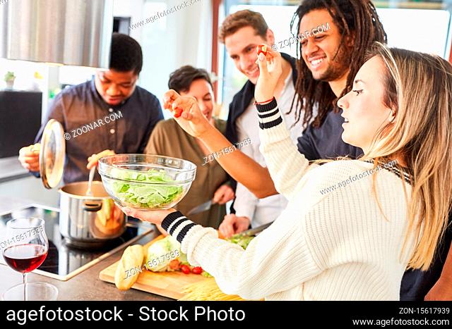 Alberne Gruppe Studenten beim gemeinsamen Kochen und Salat vorbereiten in WG Küche