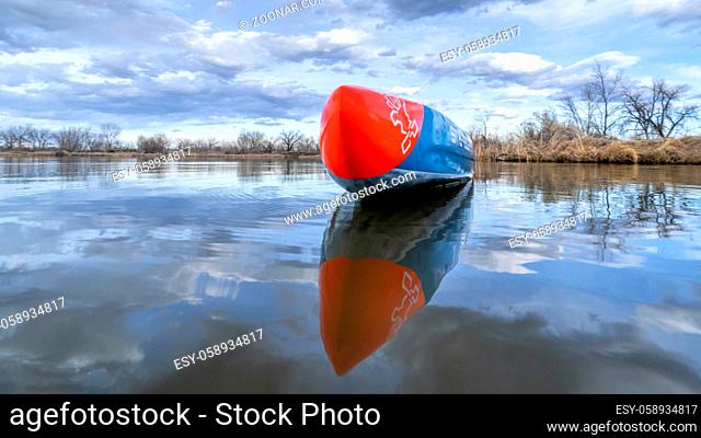 Fort Collins, CO, USA - April 27, 2020: Racing stand up paddleboard on calm lake in early spring scenery in northern Colorado - 2016 All Star versatile race...