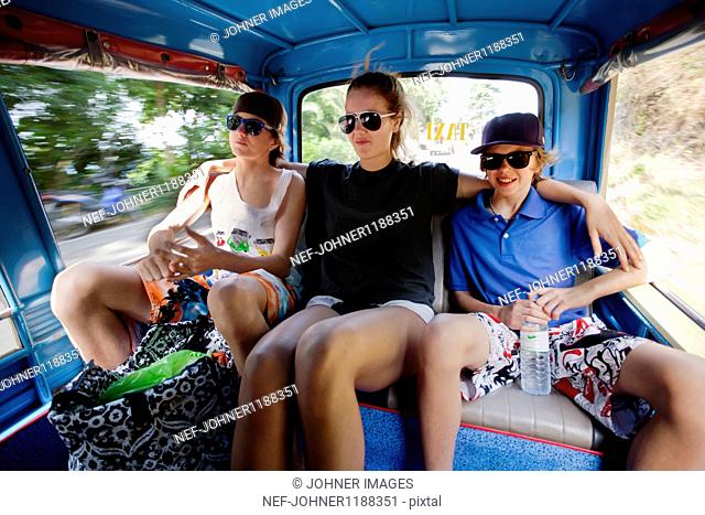Three teenagers riding in rickshaw