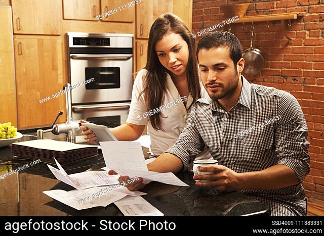 Hispanic couple looking at paperwork in kitchen