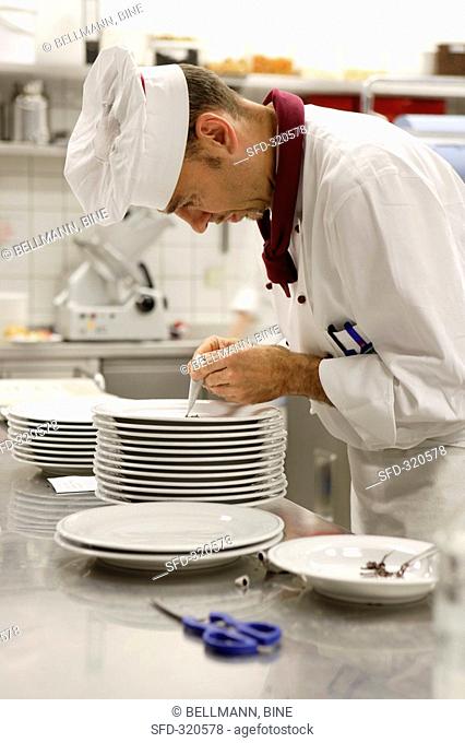 Chef decorating plate with chocolate piping