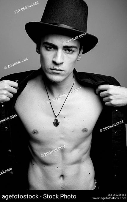Studio shot of young handsome man shirtless against gray background in black and white