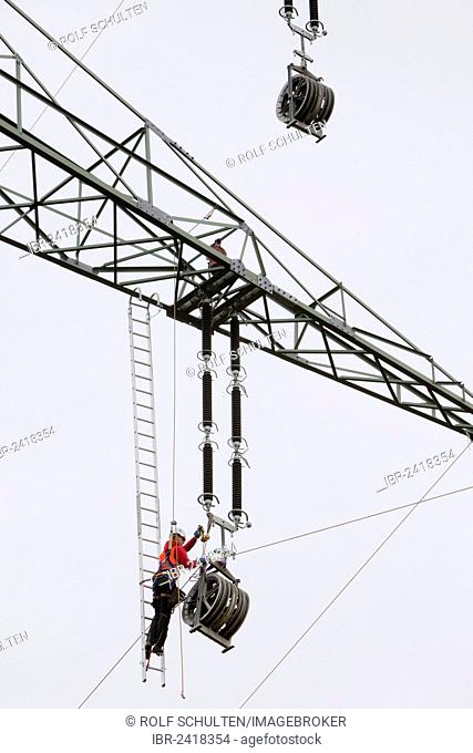 Lineman working with a wire rope hoist on a 380-kV long-distance line owned by the 50Hertz transmission system operator, track cables are being pulled from one...