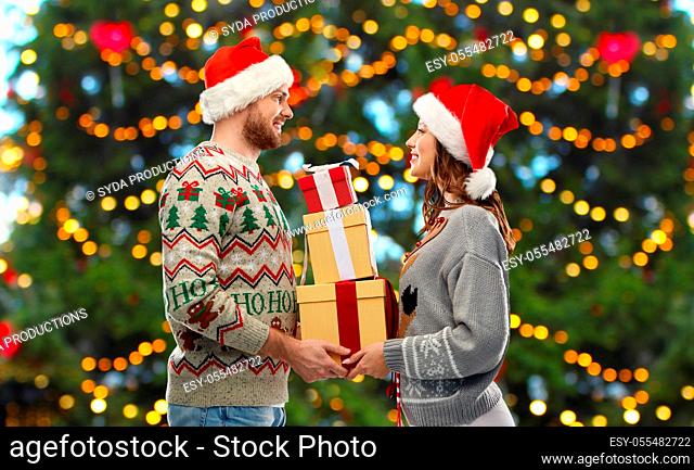 happy couple in christmas sweaters with gifts