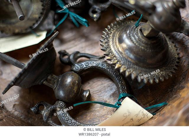 An antique store with a display of objects and furniture from the past. Chased metal decorated objects, door knocker and light fitting