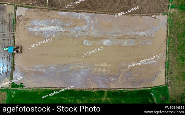 Aerial Top-down view of a tractor ploughing muddy field